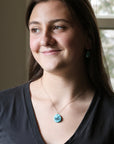 Woman wearing a necklace with a blue pendant indoors