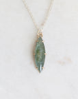 Necklace with a green stone pendant on a light gray background