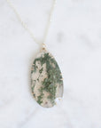Necklace with a green and white marbled pendant on a light gray background