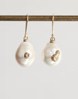 Pair of pearl earrings with gold accents on a white background