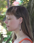Woman with hoop earrings looking to the side with trees in the background