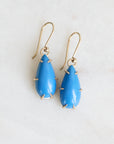 Blue teardrop earrings with gold accents on a white background