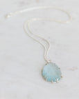 Necklace with a large teardrop-shaped green stone on a light gray background