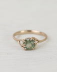 Gold ring with a green gemstone on a white fabric background