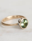 Gold ring with a green gemstone on a light background