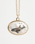 Necklace with a pendant featuring an orca whale design on a light gray background