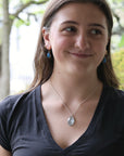 Woman wearing necklace with large blue gemstone outside