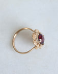 Gold ring with a red gemstone on a light gray background