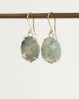 pair of green stone earrings from the side against a white background