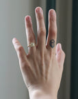 Hand wearing a gold ring with a diamond on a neutral background