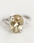 A silver ring featuring a large, oval-cut pale yellow gemstone in a prong setting, photographed on a clean white background.