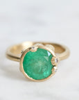 Large green gemstone ring surrounded by gold barnacles with diamonds