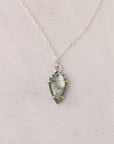 Necklace with a green crystal pendant on a light gray background