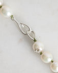 Pearl necklace with a silver clasp on a light gray background
