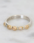 Silver ring with gold accents and a diamond on a light gray background