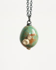 Necklace with a green marbled pendant and gold accent on a white background
