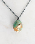 Necklace with a green and gold bead pendant on a light background