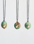 Three necklaces with green bead pendants on a white background