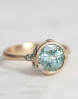 Gold ring with a large blue gemstone on a light gray background