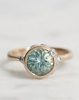 Ring with a green gemstone and silver setting on a light gray background