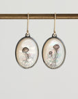 Oval-shaped earrings with jellyfish design on a gray background