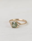 Gold ring with a green gemstone on a light gray background