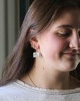 Woman wearing earrings with a neutral background