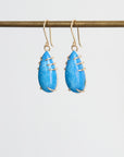Pair of blue teardrop earrings with gold accents on a white background