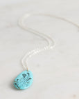 Turquoise pendant necklace on a white marble surface