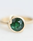Green gemstone set in gold bezel with barnacle details