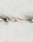 Pearl necklace with gold clasp on a light gray background