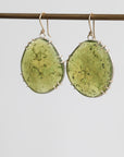 Green oval earrings with silver accents on a light gray background