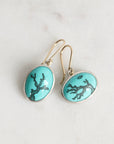 Turquoise earrings with silver accents on a light gray background