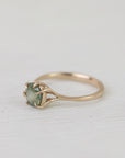 Gold ring with a green gemstone on a white fabric background