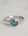 Silver ring with a blue gemstone on a light gray background