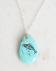 Turquoise pendant with fish design on a white background