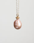 Pearl necklace with a gold clasp on a light gray background