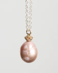 Pearl necklace with a gold clasp on a light gray background