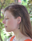 Woman with hoop earrings looking to the side with a blurred green background