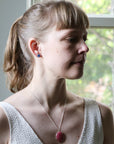 Woman wearing a necklace with a red pendant in front of a window
