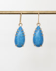 Pair of blue teardrop earrings with gold accents on a white background