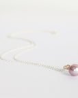Necklace with a pink pearl pendant on a light gray background