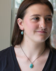 Woman wearing turquoise earrings and a necklace indoors