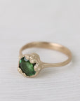 Gold ring with green gemstone on a white background
