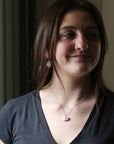Woman wearing a necklace with a pendant indoors
