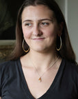 Woman wearing large hoop earrings and natural colored necklace
