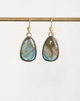 A pair of teardrop-shaped labradorite dangle earrings with gold hooks, hanging from a gold horizontal bar against a clean white background.