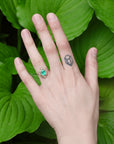 Green stone surrounded by golden rose setting on hand