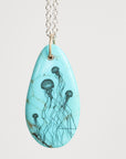 Teardrop-shaped pendant with jellyfish design on a light blue background