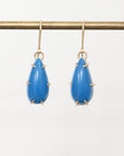 Blue teardrop earrings with gold accents on a white background